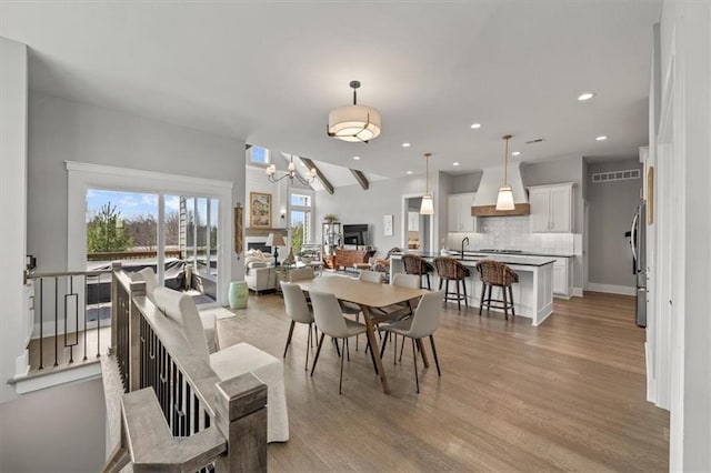 dining area with recessed lighting, baseboards, light wood-type flooring, and an inviting chandelier