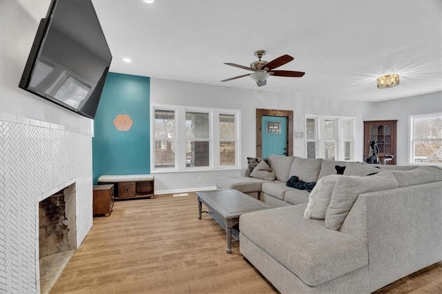 living room featuring a ceiling fan, recessed lighting, light wood-style floors, a fireplace, and baseboards