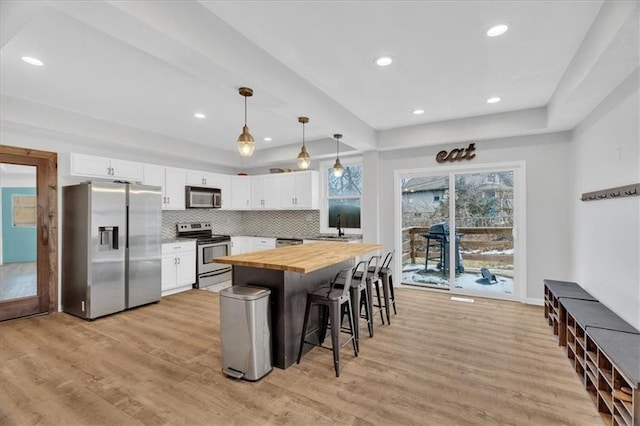 kitchen with light wood-type flooring, backsplash, appliances with stainless steel finishes, and butcher block counters