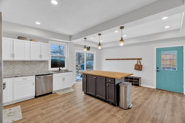 kitchen with light wood finished floors, a sink, white cabinetry, and stainless steel dishwasher