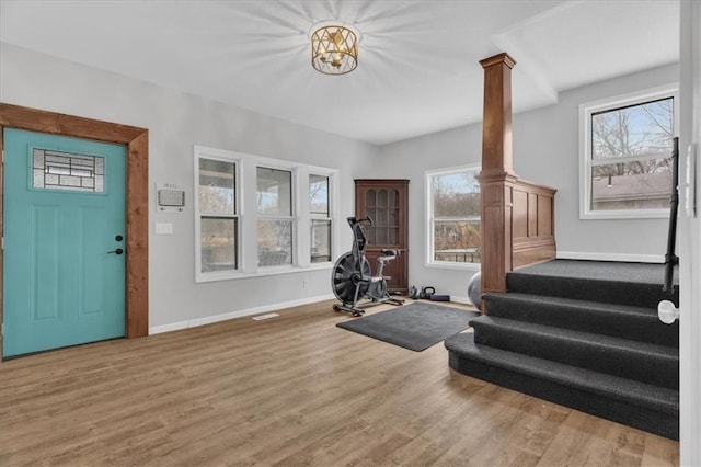 foyer entrance with decorative columns, baseboards, and wood finished floors