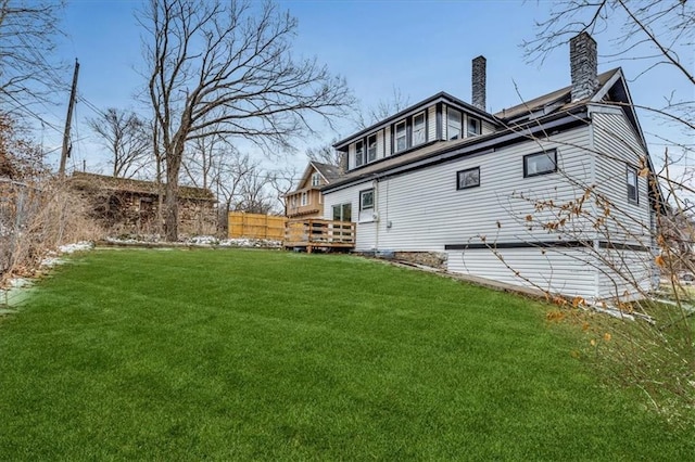 back of property featuring a yard, a deck, and a chimney