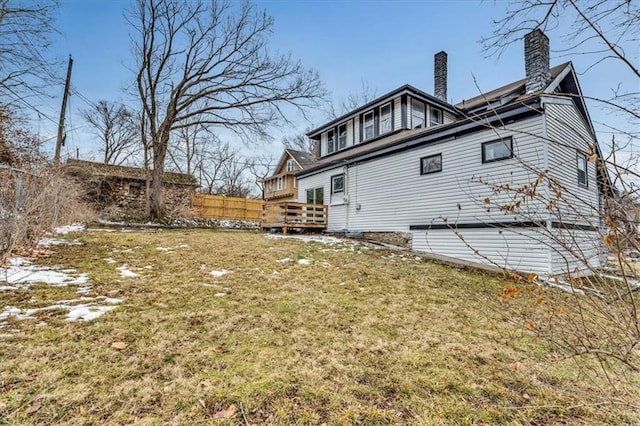 back of house featuring a deck, a lawn, and a chimney