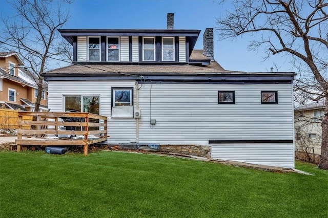 rear view of property featuring a yard, a wooden deck, and a chimney