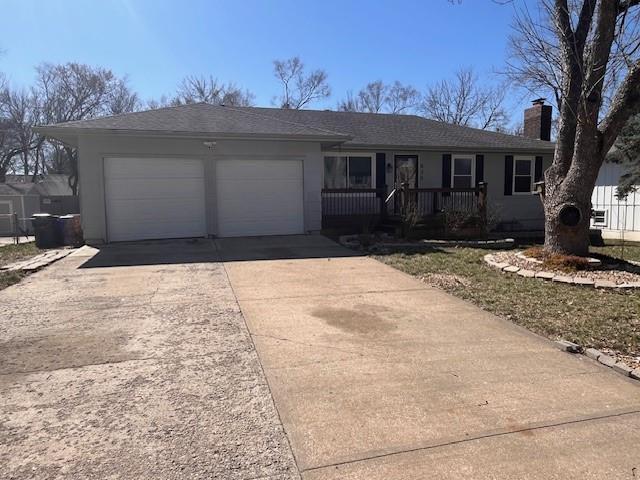 single story home featuring roof with shingles, covered porch, a chimney, a garage, and driveway