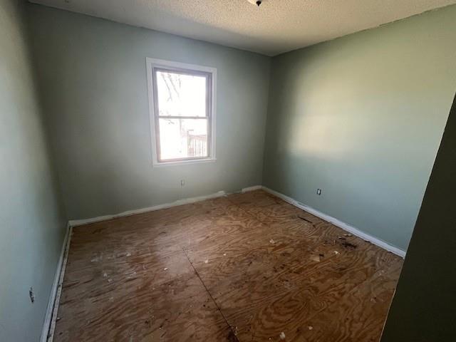 empty room with baseboards and a textured ceiling