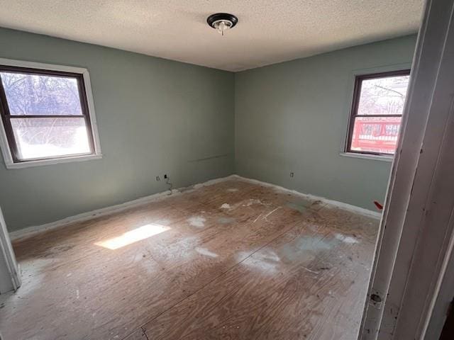 unfurnished room with a textured ceiling and a healthy amount of sunlight