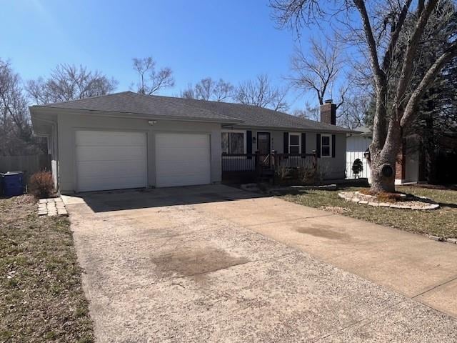 ranch-style house featuring a porch, roof with shingles, concrete driveway, a garage, and a chimney