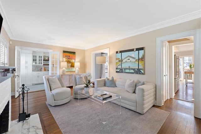 living room with a high end fireplace, hardwood / wood-style flooring, a wealth of natural light, and ornamental molding