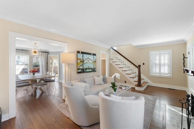 living area with stairs, crown molding, wood finished floors, and baseboards