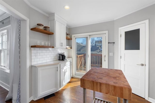 dining room featuring dark wood-type flooring, visible vents, baseboards, and ornamental molding