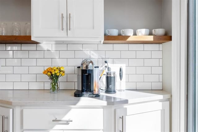 interior details featuring tasteful backsplash, white cabinetry, and open shelves