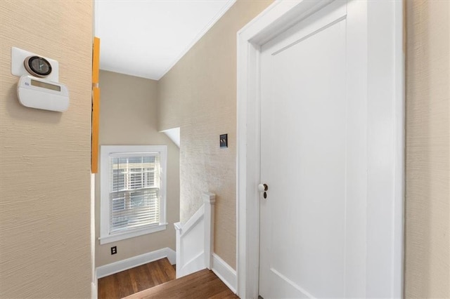 corridor with an upstairs landing, wood finished floors, and baseboards