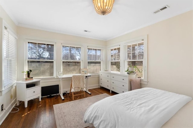 bedroom with crown molding, wood finished floors, visible vents, and baseboards