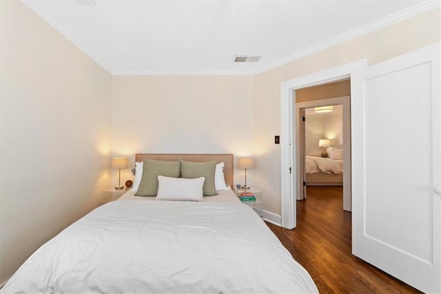 bedroom featuring dark wood finished floors, baseboards, visible vents, and ornamental molding