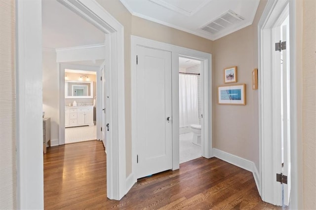 corridor featuring visible vents, ornamental molding, baseboards, and dark wood-style flooring