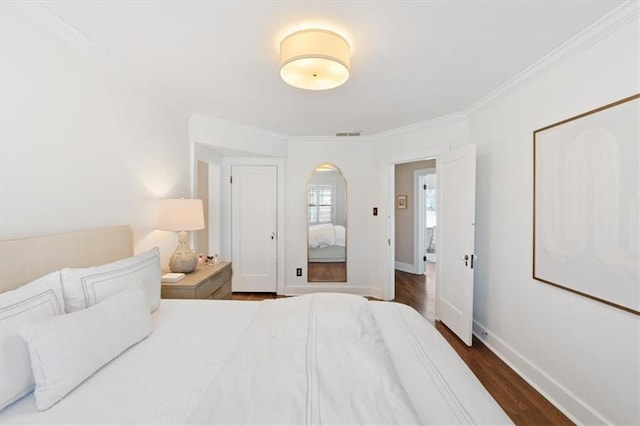 bedroom with dark wood-style floors, visible vents, baseboards, and ornamental molding