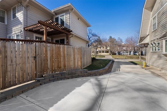 view of home's exterior with a patio, concrete driveway, and fence