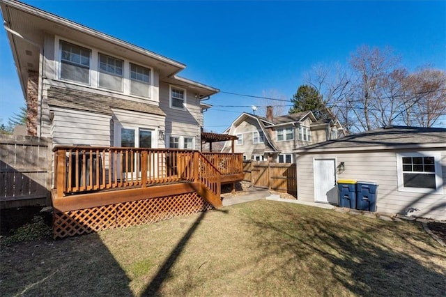 rear view of property with an outdoor structure, a wooden deck, a yard, and fence