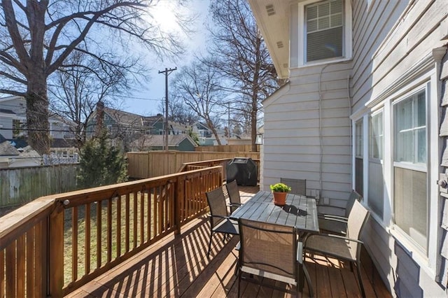 wooden deck with a fenced backyard and outdoor dining space