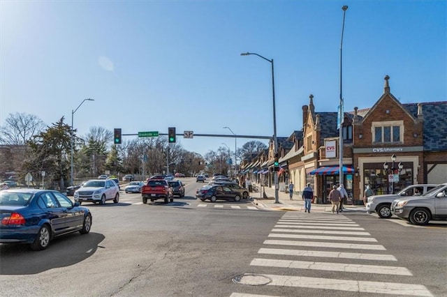 view of road featuring sidewalks, street lighting, and traffic lights