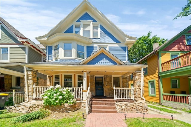 victorian-style house with stone siding and covered porch