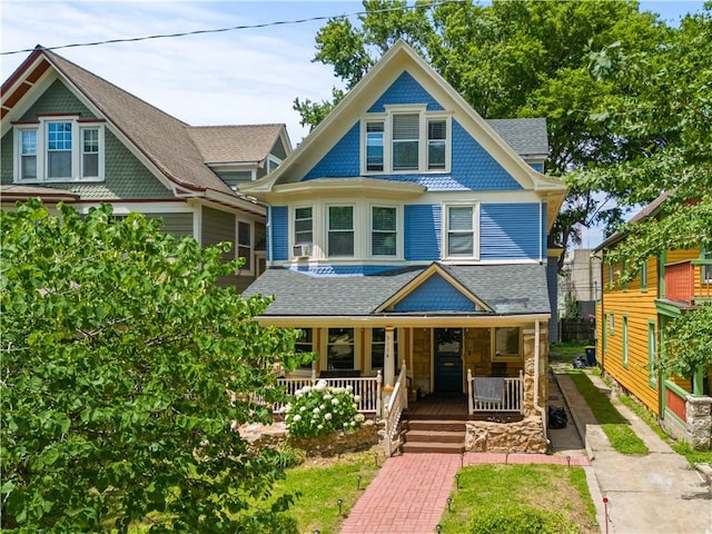 victorian home with covered porch and roof with shingles