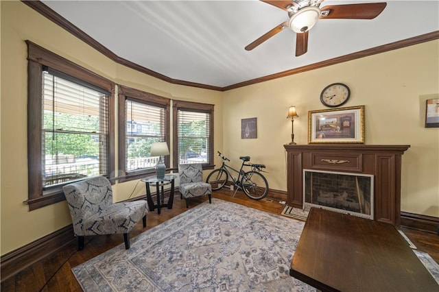 sitting room featuring baseboards, wood-type flooring, ornamental molding, and a fireplace with flush hearth