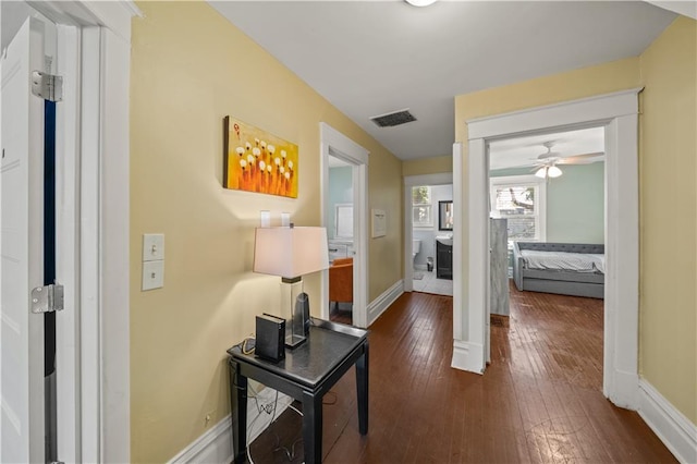 hallway featuring baseboards, visible vents, and dark wood-style flooring