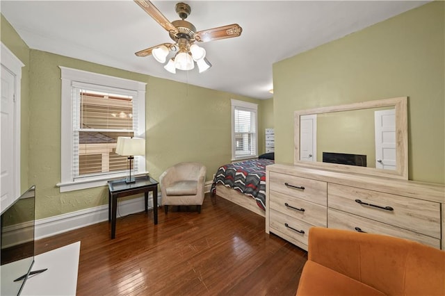 bedroom with ceiling fan, baseboards, dark wood finished floors, and a textured wall