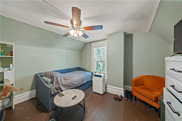 bedroom with a textured wall, baseboards, wood-type flooring, and vaulted ceiling