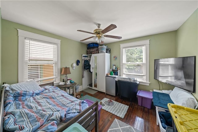 bedroom with wood-type flooring, refrigerator, and ceiling fan