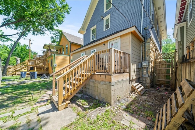 rear view of property featuring stairs, fence, and a wooden deck