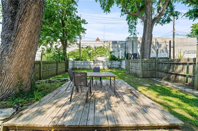 wooden deck featuring outdoor dining space, a yard, and a fenced backyard