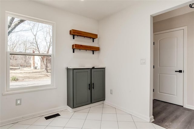 interior space featuring light tile patterned floors, visible vents, and baseboards