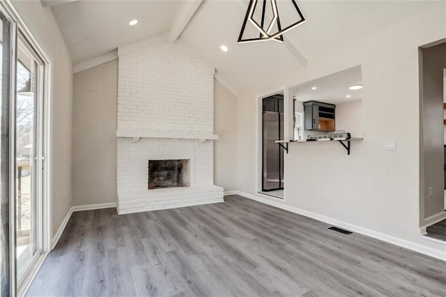 unfurnished living room featuring visible vents, wood finished floors, a fireplace, baseboards, and vaulted ceiling with beams