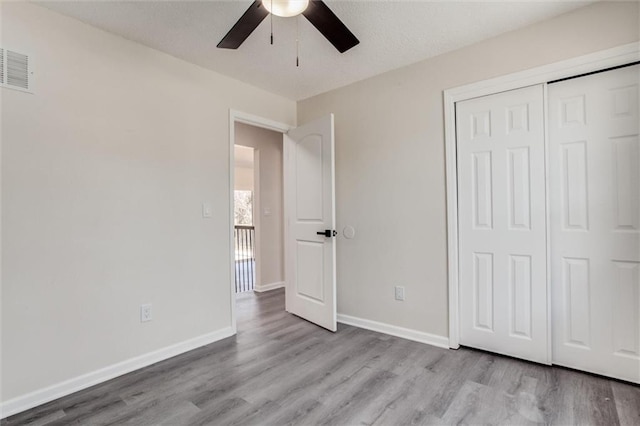 unfurnished bedroom with visible vents, a ceiling fan, wood finished floors, a closet, and baseboards