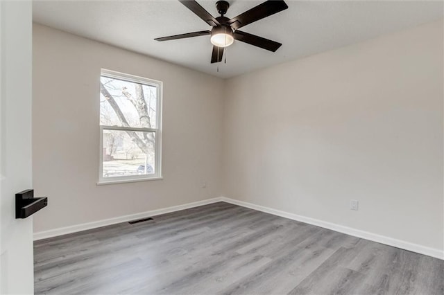 unfurnished room with wood finished floors, visible vents, and baseboards