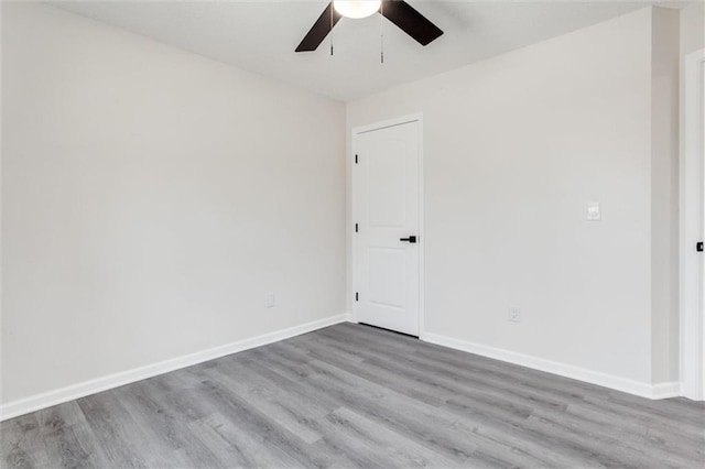 empty room with ceiling fan, baseboards, and wood finished floors