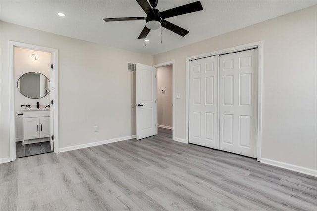 unfurnished bedroom featuring a closet, ensuite bath, baseboards, and wood finished floors