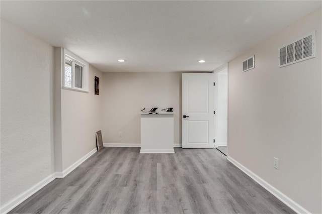 below grade area with visible vents, baseboards, and wood finished floors