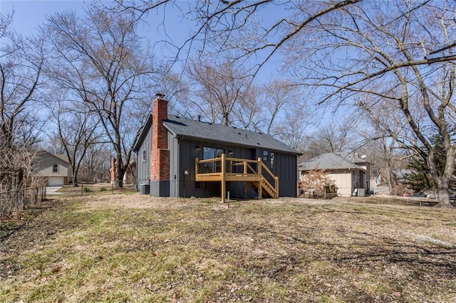 back of house with a wooden deck, stairway, board and batten siding, and a chimney