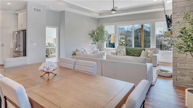 dining area featuring wood finished floors, a ceiling fan, visible vents, recessed lighting, and a raised ceiling