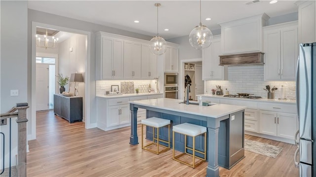 kitchen with a sink, appliances with stainless steel finishes, white cabinets, and light countertops