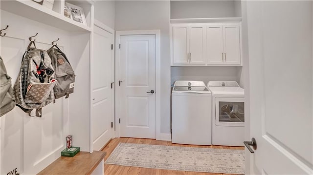 laundry room featuring washer and dryer, cabinet space, and light wood-type flooring