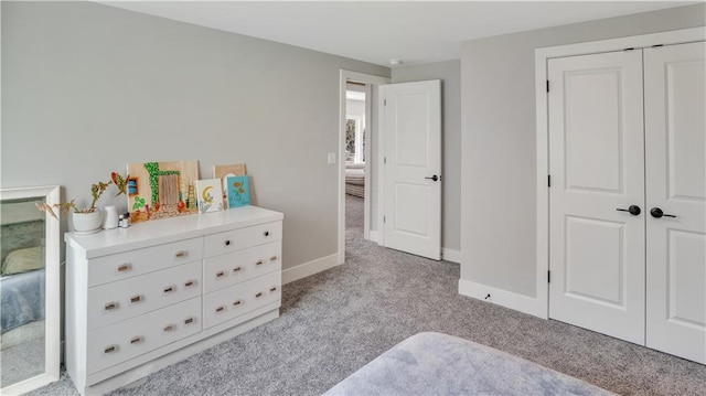 carpeted bedroom with a closet and baseboards