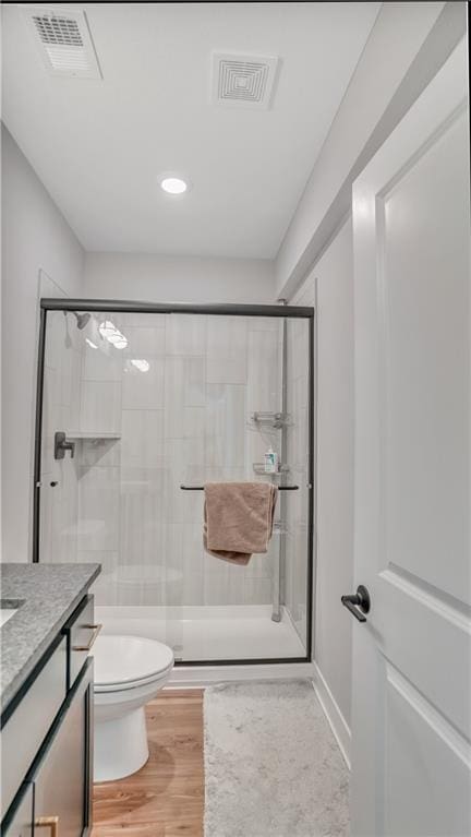 bathroom with toilet, wood finished floors, visible vents, and a stall shower