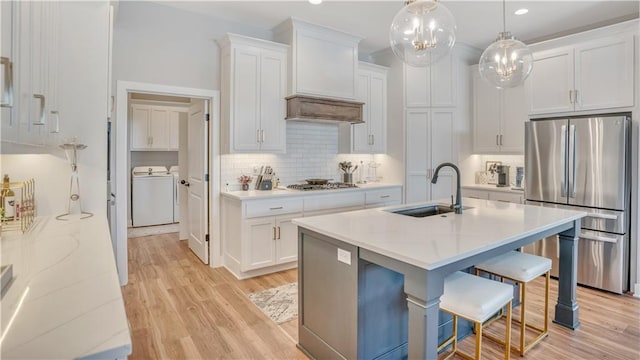 kitchen featuring light wood finished floors, appliances with stainless steel finishes, a kitchen bar, and a sink