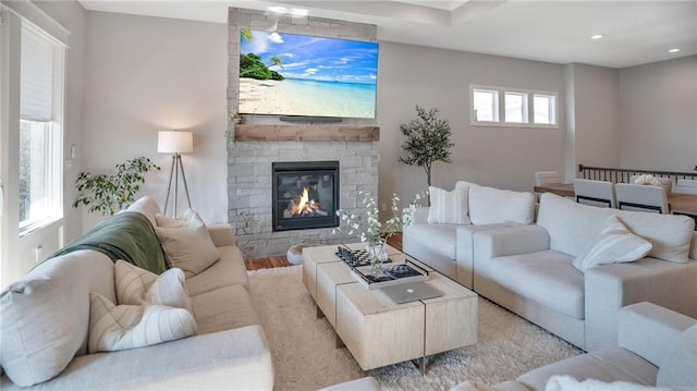 living area featuring a stone fireplace, recessed lighting, and wood finished floors