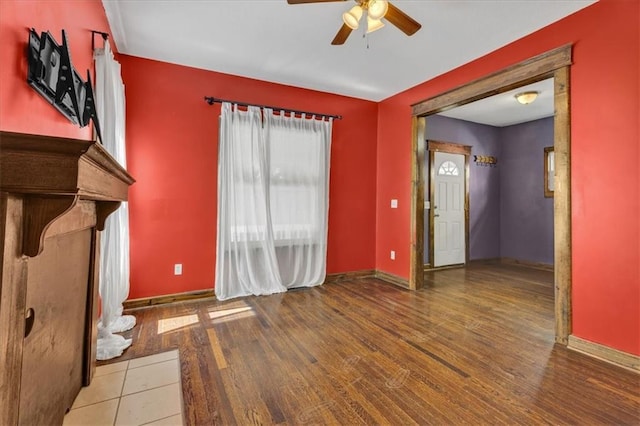 unfurnished living room with a ceiling fan, wood finished floors, and baseboards